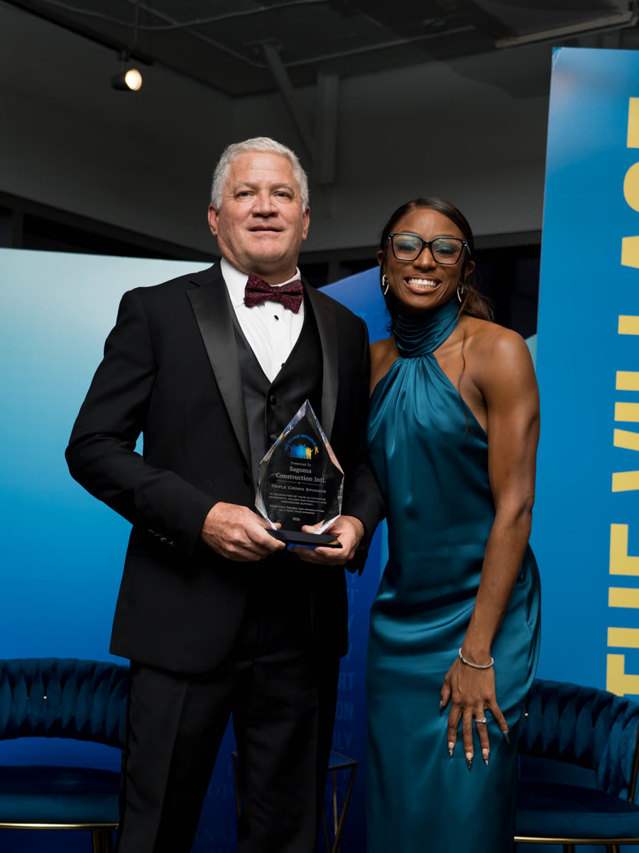 Marvin Arrington holding a glass award beside Melissa Jefferson-Wooden on stage at the gala