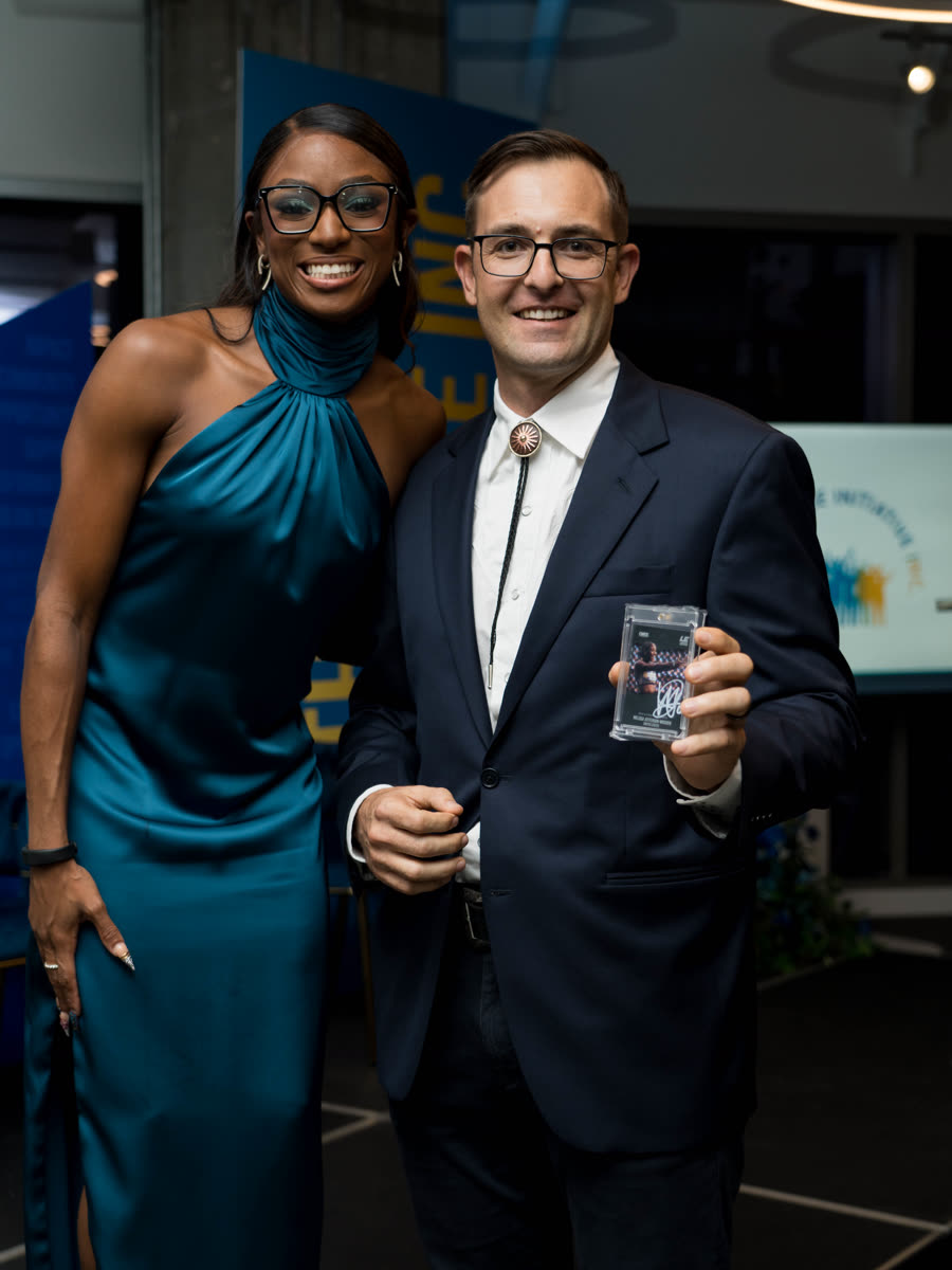 Theuns Vogel holding the signed trading card he won, beside Melissa Jefferson-Wooden at the gala